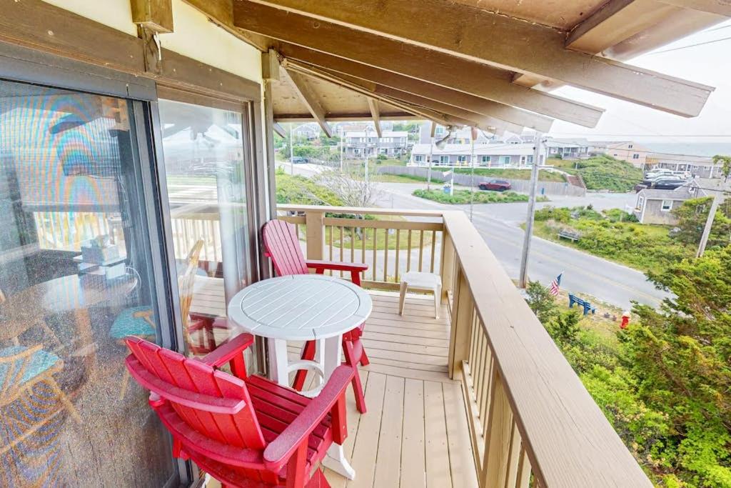 a porch with red chairs and a table on a balcony at The Pagoda Perch in North Truro