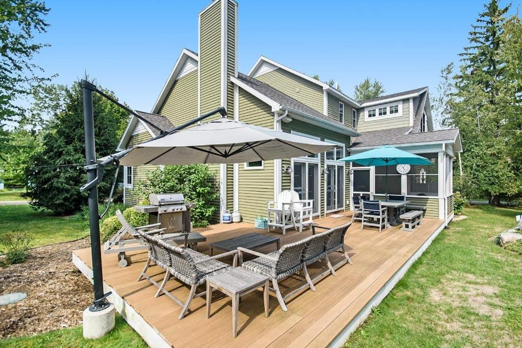 a house with a deck with chairs and an umbrella at Appy Place in South Haven