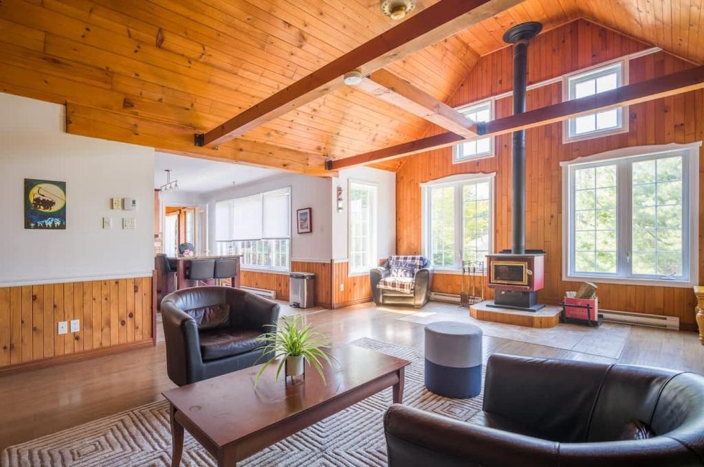 a living room with leather furniture and a wooden ceiling at Le rocher - St-Adolphe in Saint Adolphe D'Howard