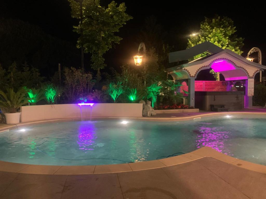 Ein beleuchteter Swimmingpool in einem Garten bei Nacht in der Unterkunft Hotel Maxim in Caorle
