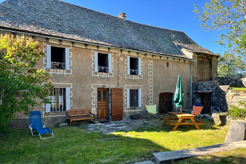 a house with chairs and a picnic table in front of it at Le Refuge de l'Argence in Alpuech
