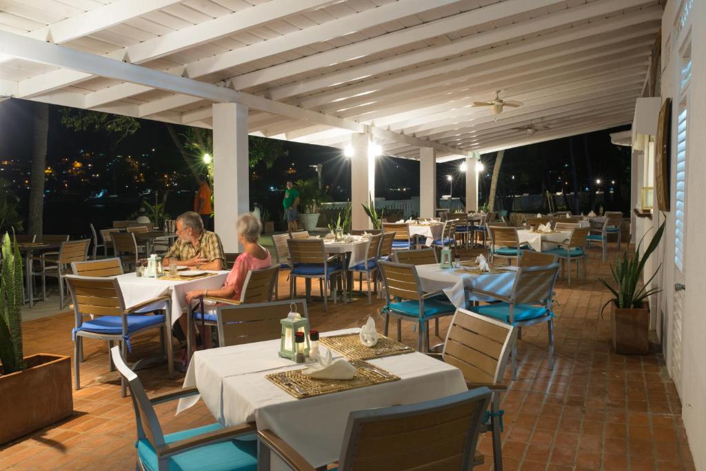 people sitting at tables on an outdoor patio at night at Bequia Plantation Hotel in Bequia