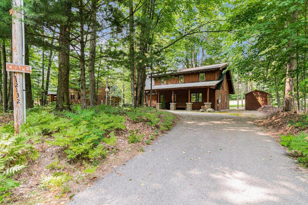 a cabin in the woods with a road leading to it at The Log Cabin in Thompsonville