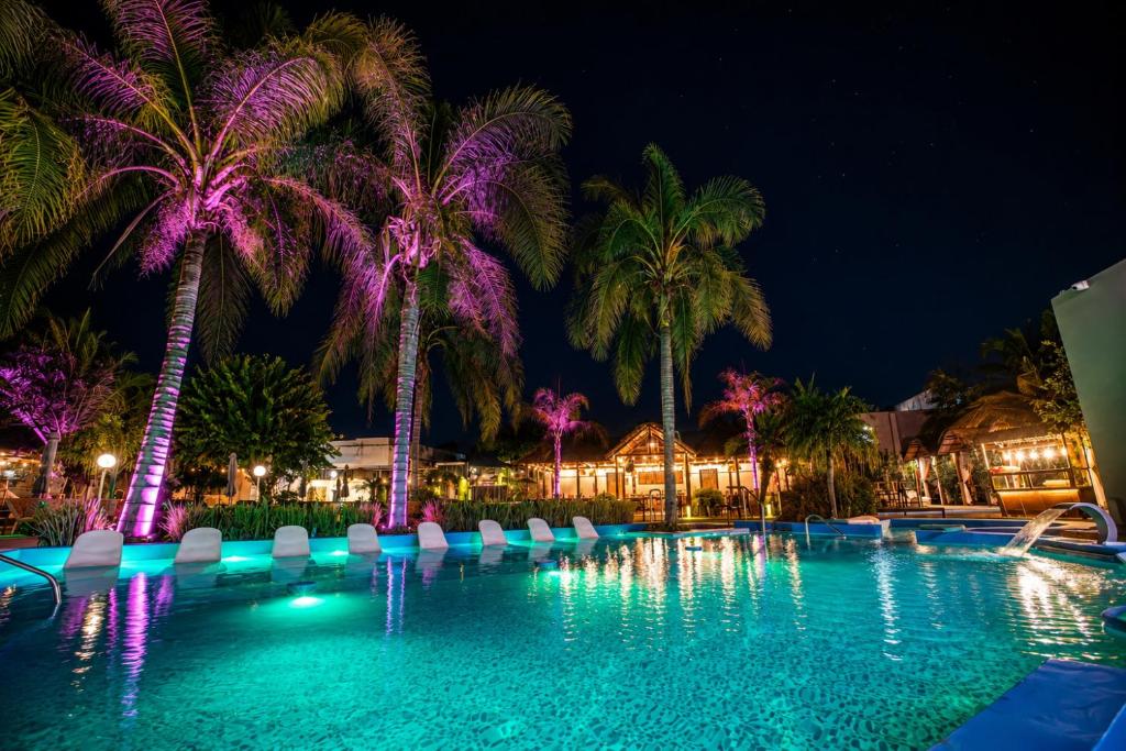 a swimming pool with palm trees at night at Hotel Termal Emperatriz Termas de Río Hondo in Termas de Río Hondo