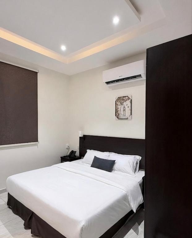 a bedroom with a large white bed with a black headboard at بستان الورد 2 in Taif
