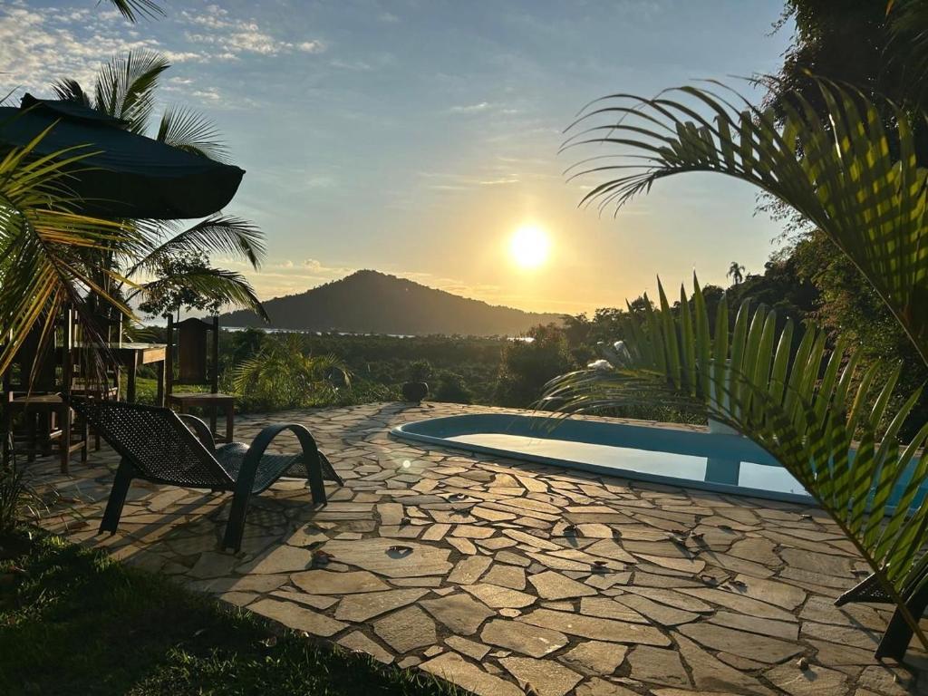 a bench sitting next to a pool with the sunset at Cantinho do marinheiro in Paraty