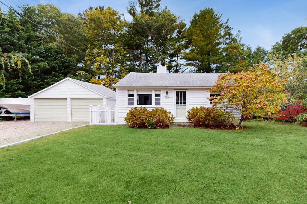 a white house with a grass yard at The Kettle Cottage in Cotuit