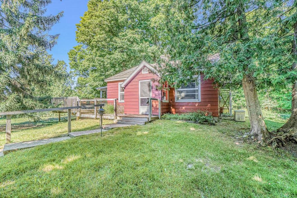 a red house with a tree and a fence at Hal's Hideaway in Beulah