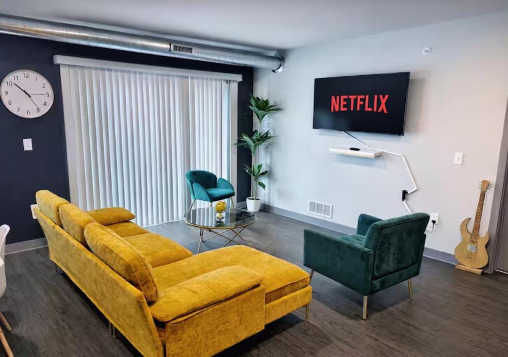 a living room with a yellow couch and two green chairs at Golden Fern Escape in Des Moines