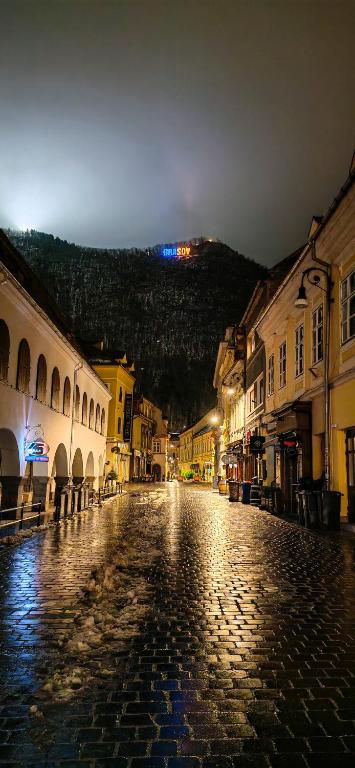 a cobblestone street in an old town at night at Modest Ultra Central Apartment Council Square in Braşov