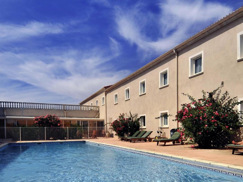 a building with a swimming pool in front of a building at ibis Orange Sud in Orange