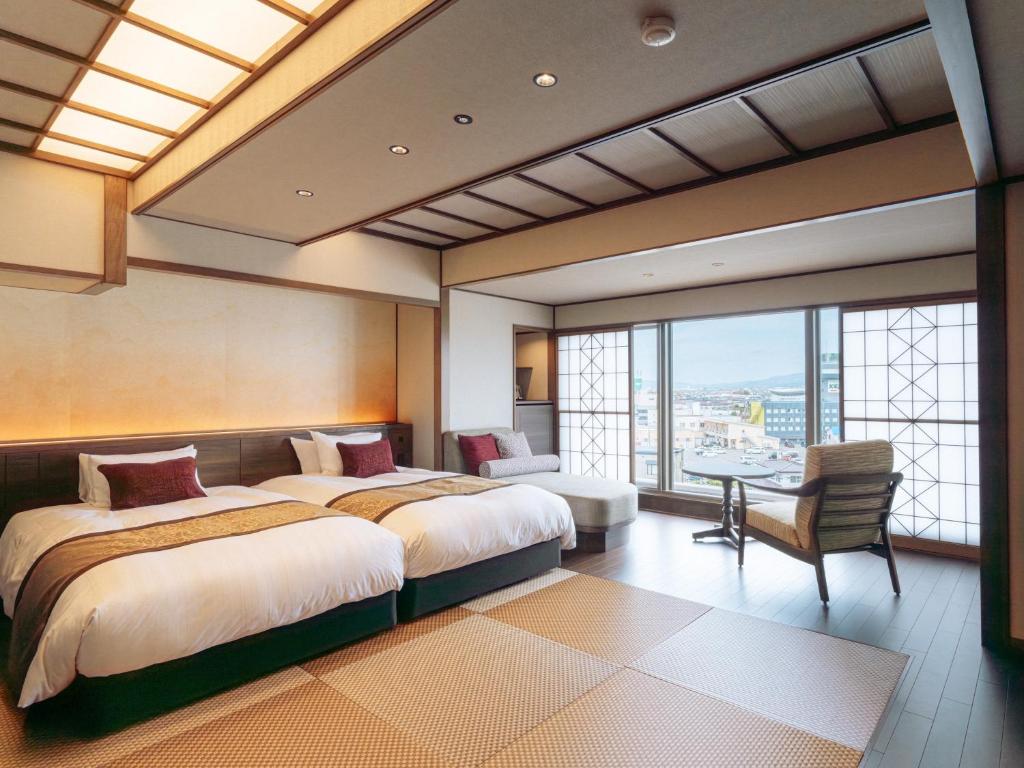 a bedroom with two beds and a desk and a window at Hanabishi Hotel in Hakodate