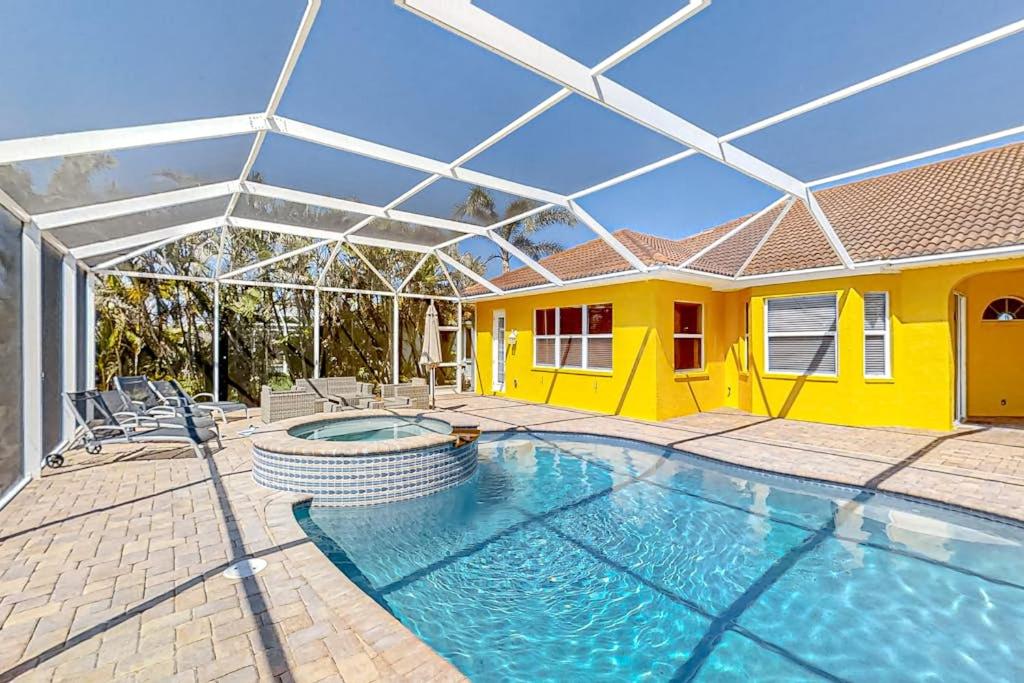 a house with a swimming pool and a yellow house at Waterfront Hideaway in Cape Coral
