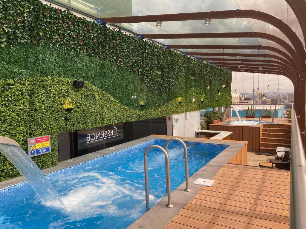 a swimming pool with a wall of plants at Mercure Alameda Quito in Quito