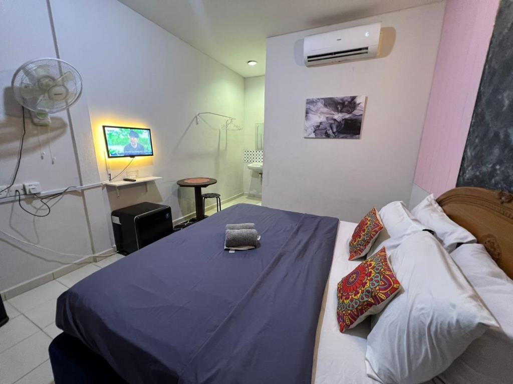 a bedroom with a bed with a blue blanket and a fan at Little Chenang Cottage Motel Langkawi in Pantai Cenang