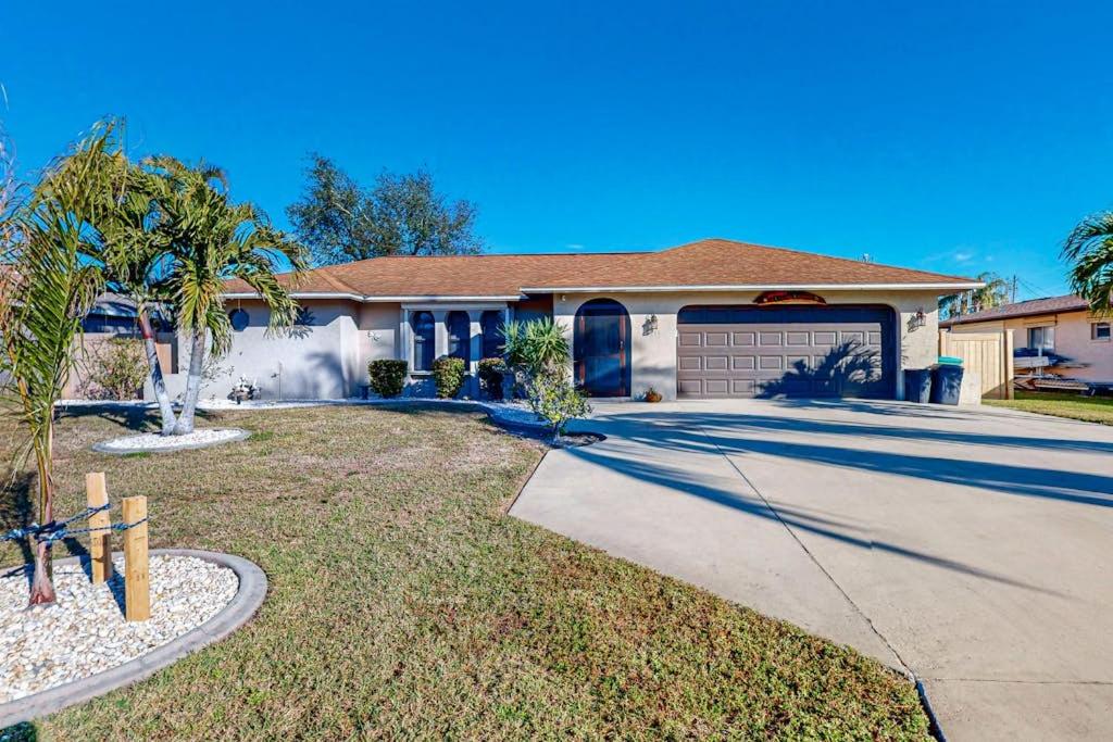 a house with a palm tree and a driveway at Cape Escape in Cape Coral