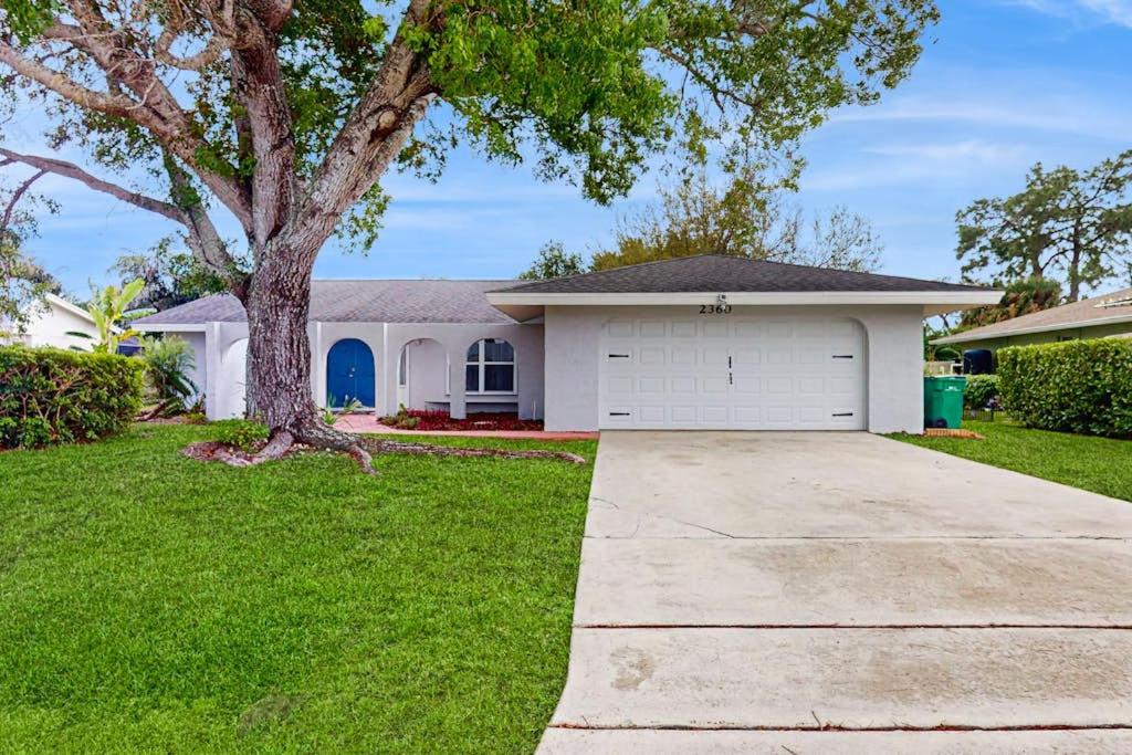 a white house with a tree and a driveway at The Flip Flop Stop in Naples