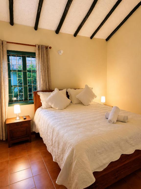 a bedroom with a bed with white sheets and two lamps at Hotel Altair in Villa de Leyva