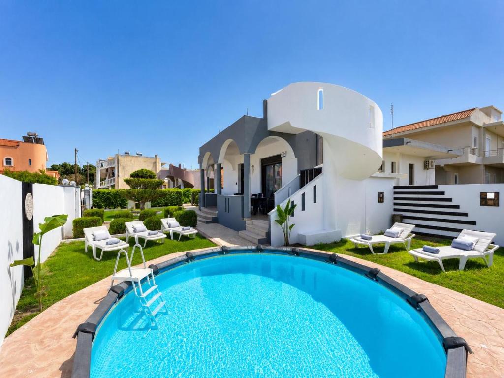 a villa with a swimming pool in front of a house at Rhodian Villa in Kremasti