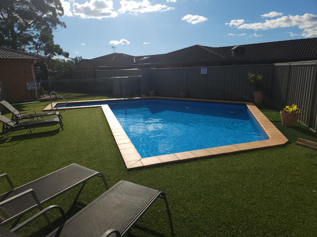 a large swimming pool in a yard with grass at Port O'Call Motel in Port Macquarie