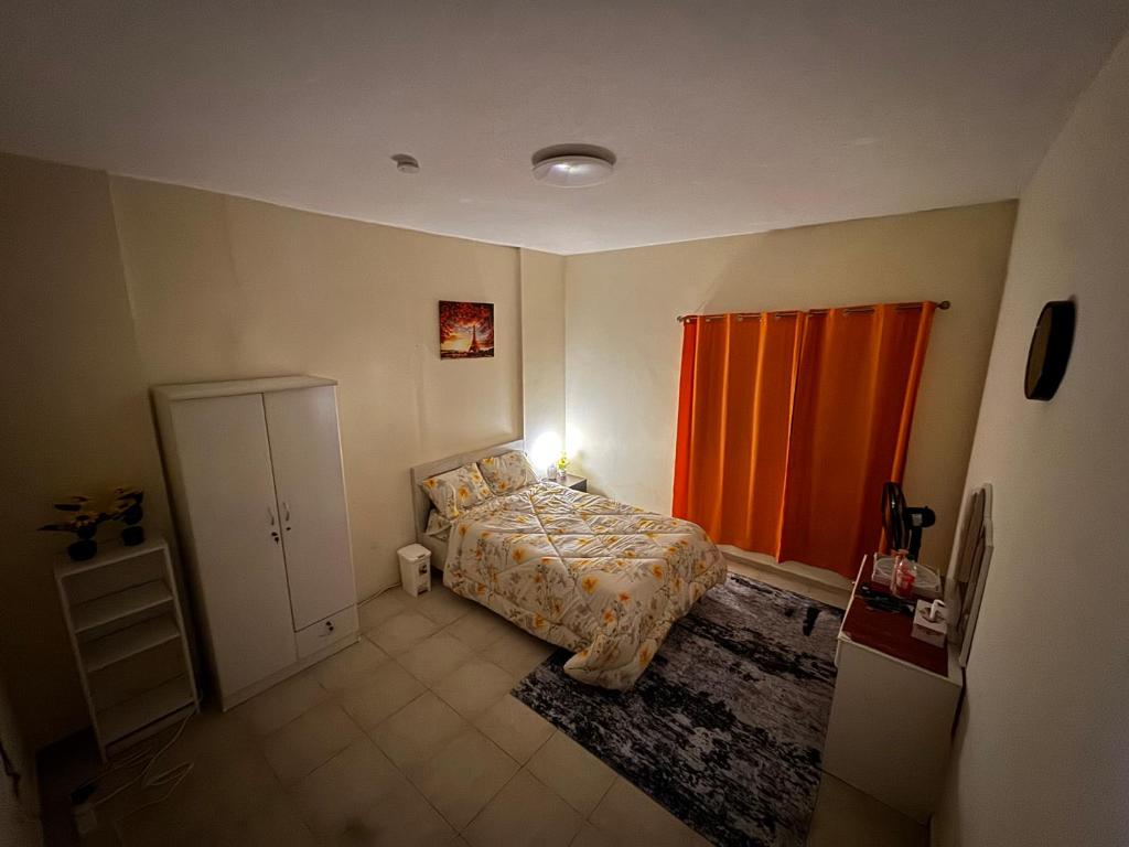 a bedroom with a bed and an orange curtain at Abdulla al Shaiba in Jazīrat al Ḩibāb