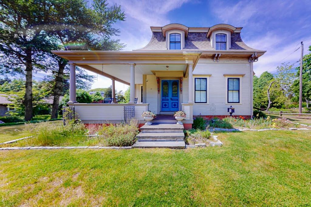 a white house with a blue door on a yard at Old Mansard in West Dennis