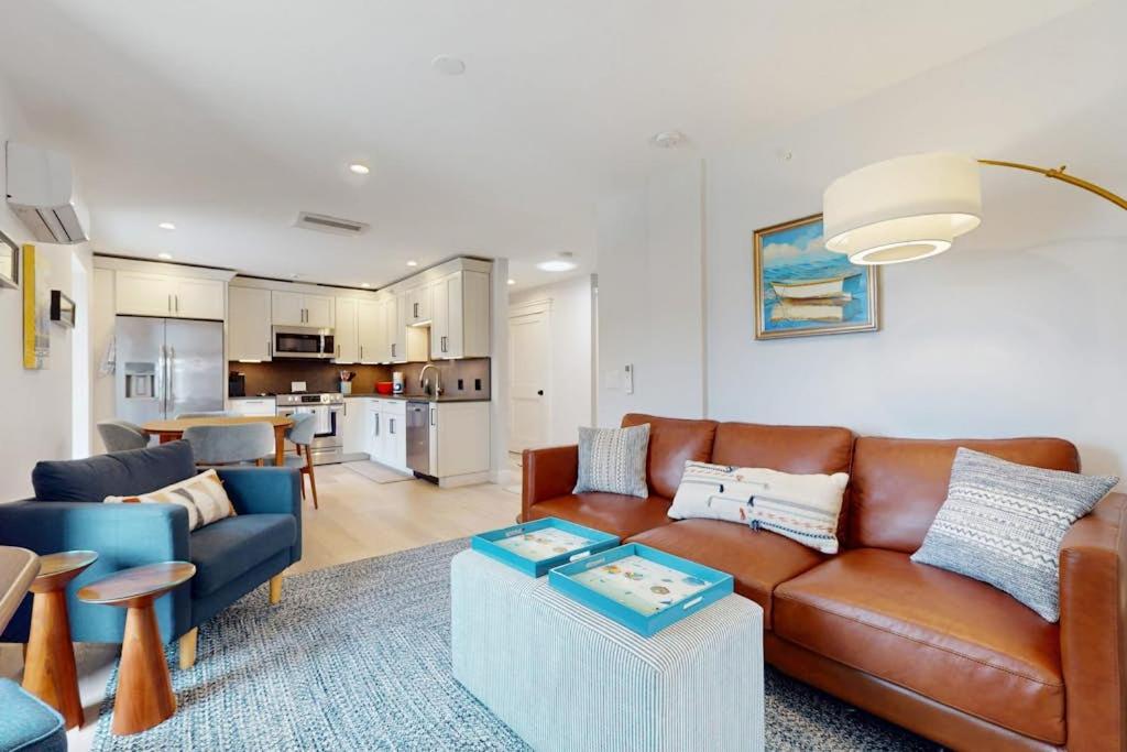 a living room with a brown leather couch and a kitchen at Fun in the Sun in Provincetown