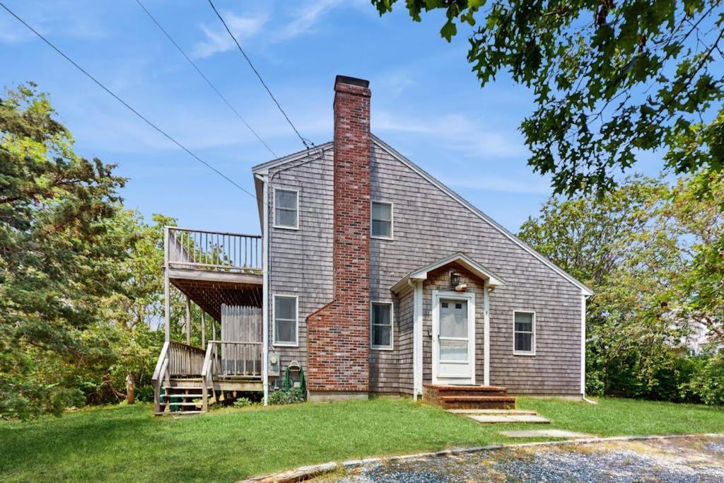 a brick house with a porch and a balcony at Sandpiper's Saltbox in Dennis