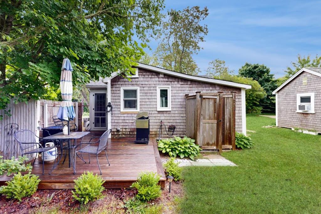 a wooden deck with a table and an umbrella at Cozy Escape on the Cape in Eastham