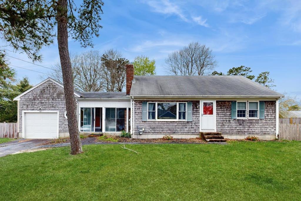 a white house with a tree in a yard at Captain's Escape in South Yarmouth