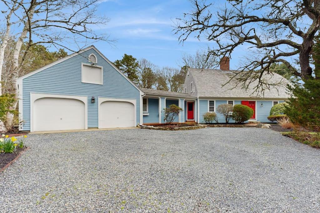 a blue house with two garage doors on a driveway at Sheep Pond Bow House in Brewster