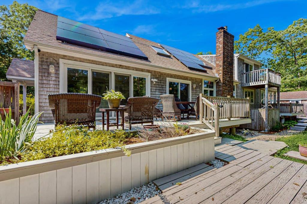 a home with a deck with chairs and a table at Sanctuary In The Woods in East Falmouth