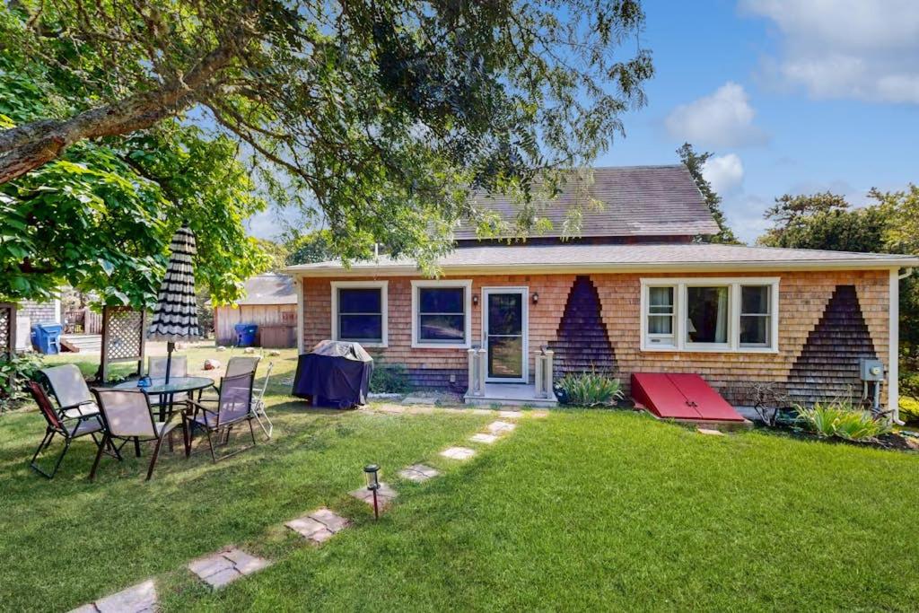 a house with a table and chairs in the yard at Oak Leaf Cape Cottage in Oak Bluffs