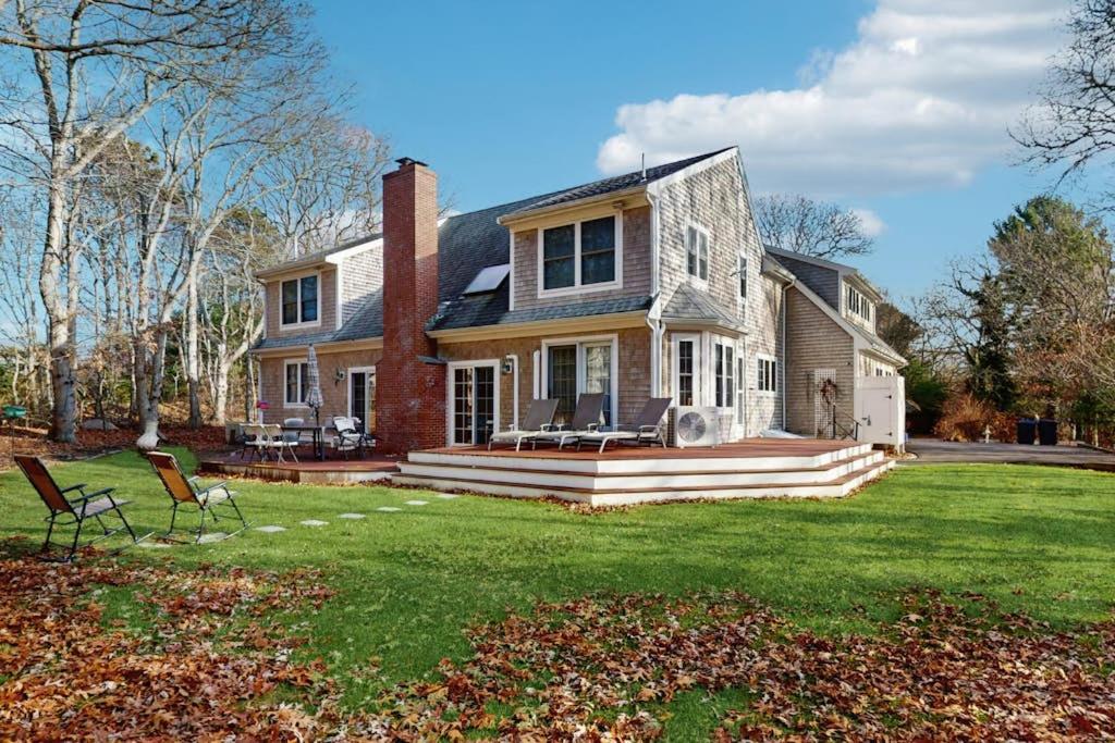 a house with a lawn with two chairs in front of it at Sandbar Hideaway in Falmouth