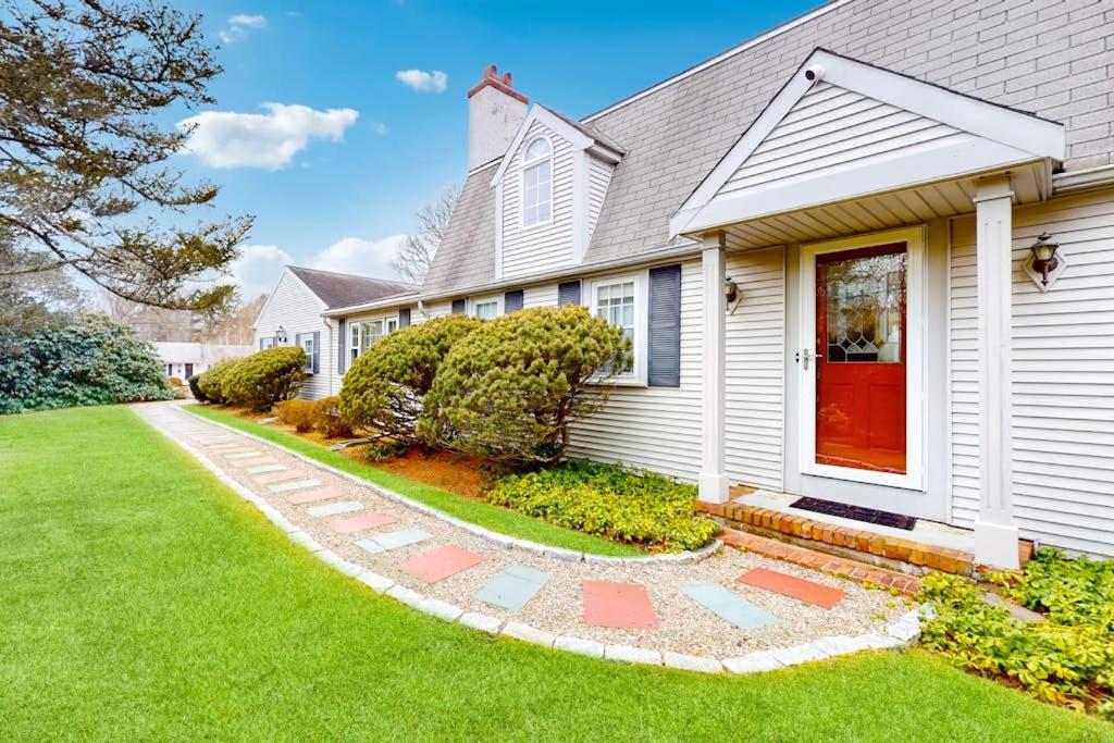 a white house with a red door and a yard at Coastal Charm on the Cape in Centerville