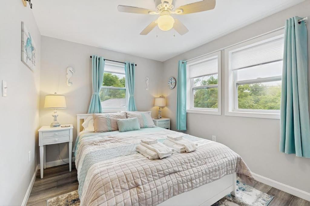 a bedroom with a bed with a ceiling fan and windows at Garage Suite in Oak Bluffs