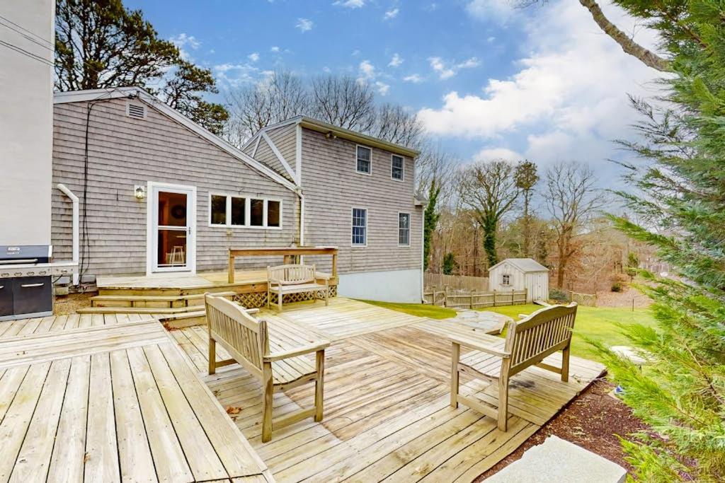 a backyard with a wooden deck with two benches at Saltwater Haven in Orleans