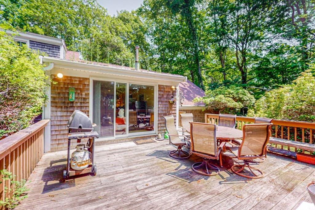 a wooden deck with chairs and a grill on a house at Falmouth Beachtown Getaway in Falmouth