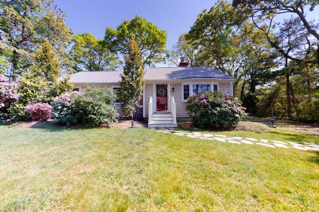 a white house with a red door in a yard at Meet Me at the Cape in Barnstable