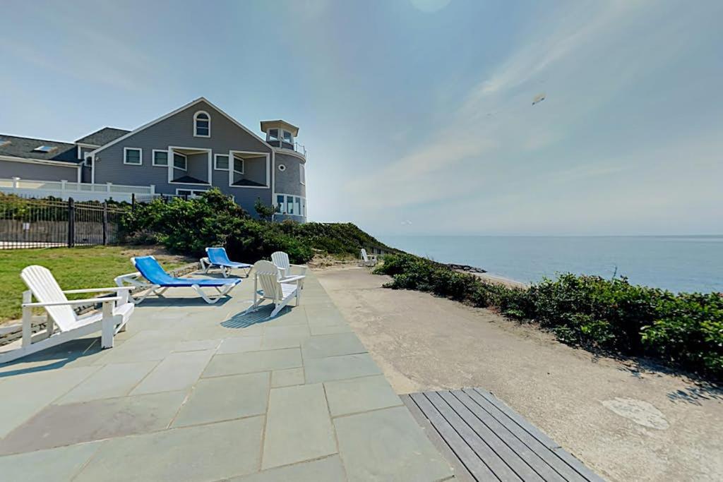 a patio with chairs and a house and the ocean at Immaculate Beach Condo in Dennis Port