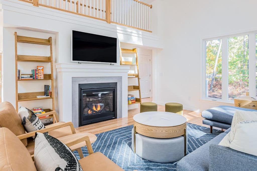 a living room with a fireplace with a flat screen tv at Peace Among the Pines in Wellfleet