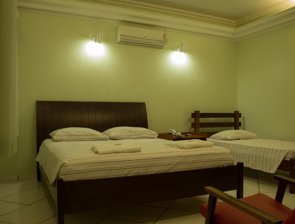 a bedroom with two beds with towels on them at Hotel Barão Do Rio Branco in Bebedouro