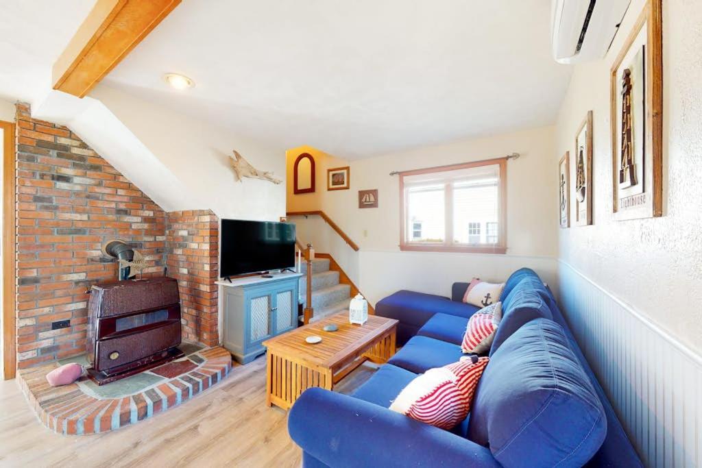 a living room with a blue couch and a fireplace at Swift Beach House in Wareham