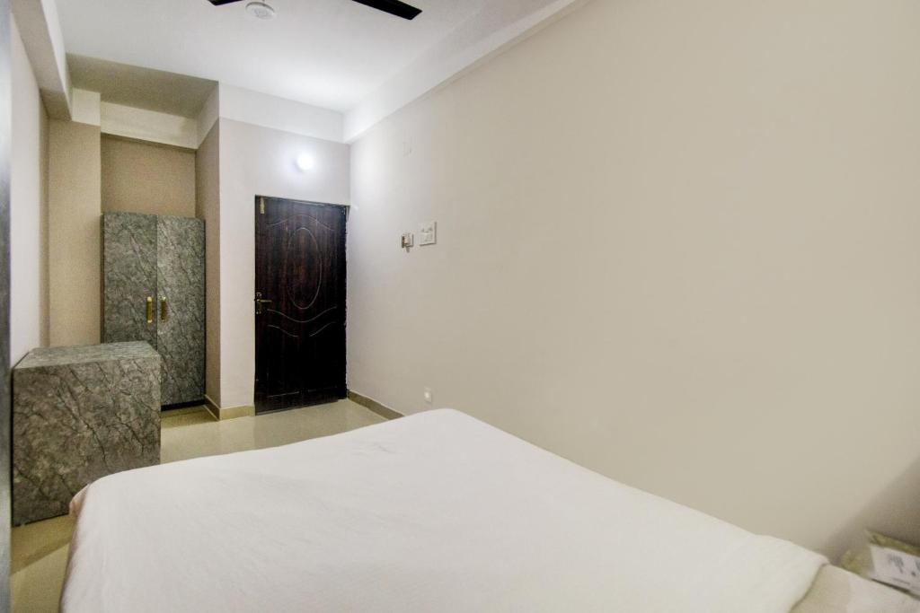 a bedroom with a white bed and a black door at Hotel O Sai villa in Dispur