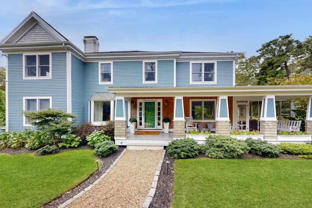 a blue house with a porch and a lawn at Bird's Paradise in Oak Bluffs