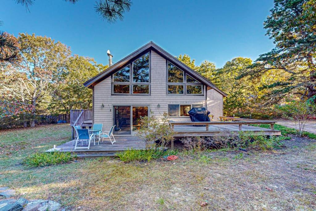 a house with a porch and two chairs on a field at Cozy Island Cabin in Edgartown