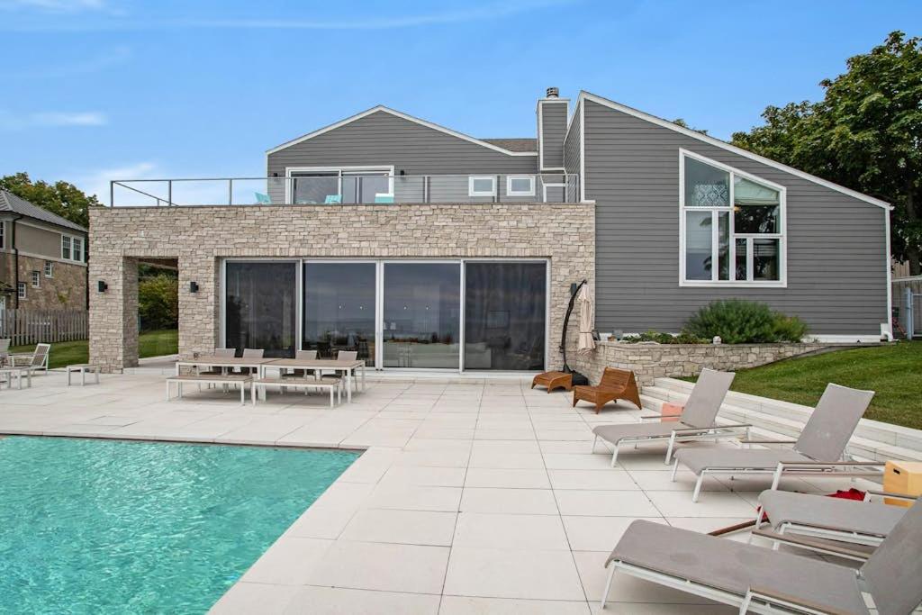 a swimming pool with lounge chairs and a house at Leisure On The Lake in New Buffalo