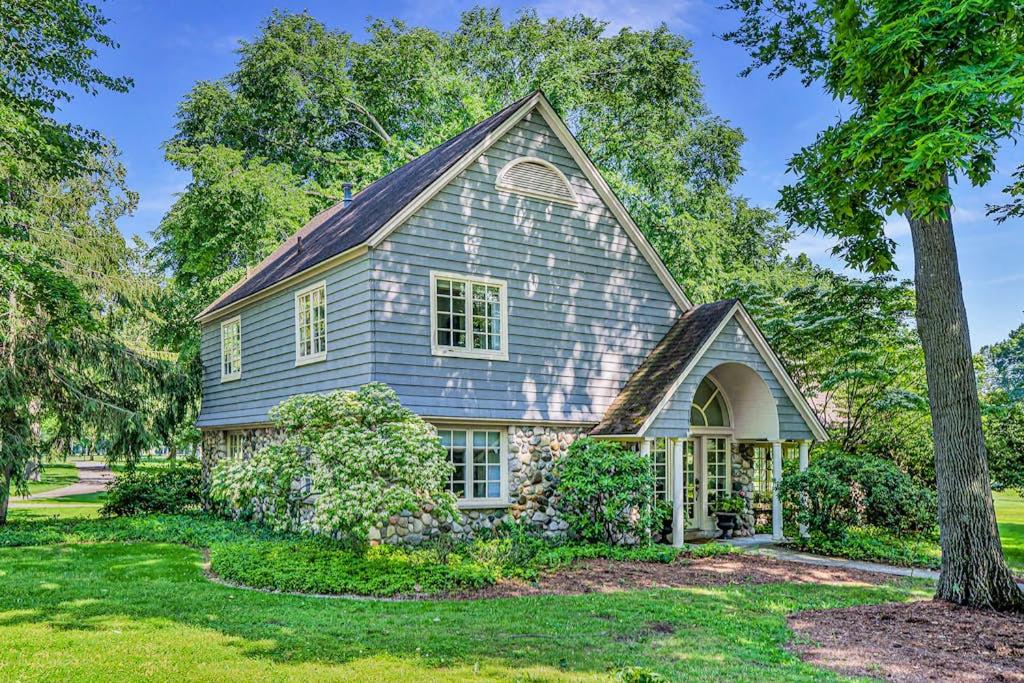 a blue house with a tree in the yard at Point Cottage at Point O' Woods in Benton Harbor