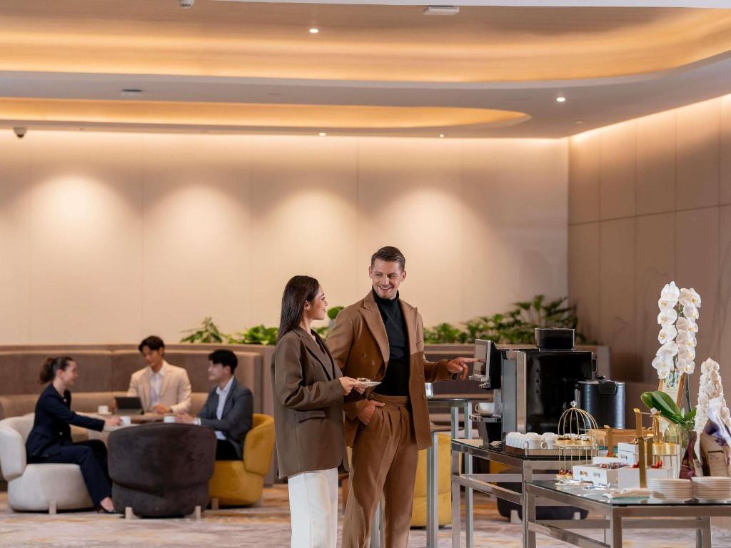 A softly lit lobby reception area with a welcome desk, lounge seating and a refreshment display.