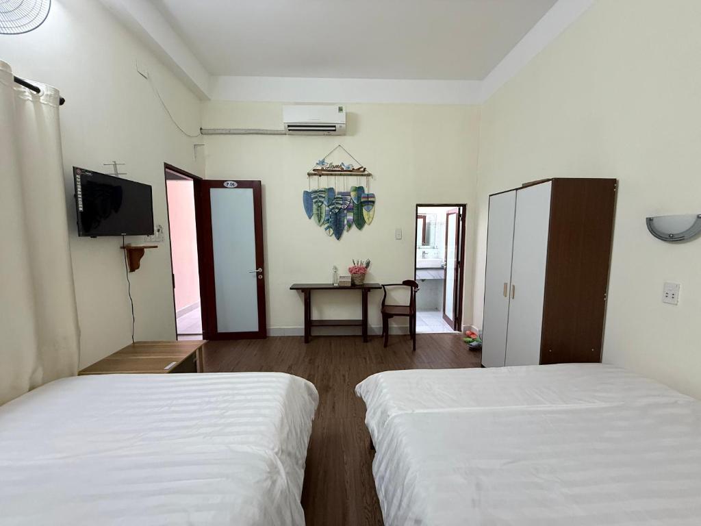 two beds in a room with a table and a tv at Ba Doan 2 in Con Dao